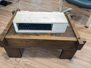 a closed wooden box with a keyboard visible through a hole in the front