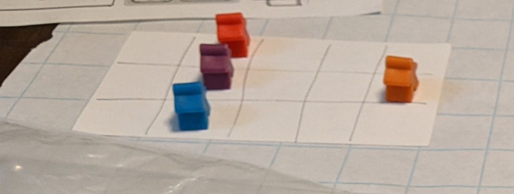 Four meeples on an index card, representing a wagon.
